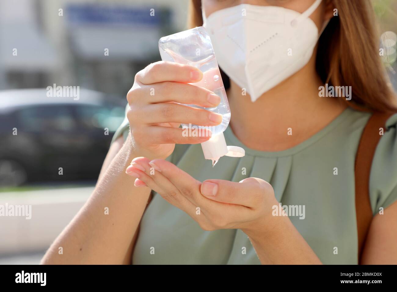 COVID-19 Pandemic Coronavirus Close up Unidentified Woman with KN95 FFP2 Mask using Alcohol Gel Sanitizer Hands in City Street. Antiseptic, Hygiene an Stock Photo