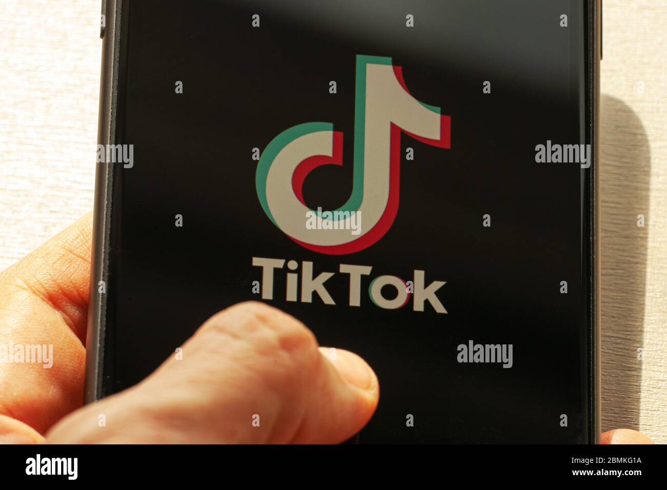 TikTok application icon on Apple iPhone 11 screen close-up. Hand holding smartphone with Tik Tok icon.  Tiktok Social media network from China. Stock Photo
