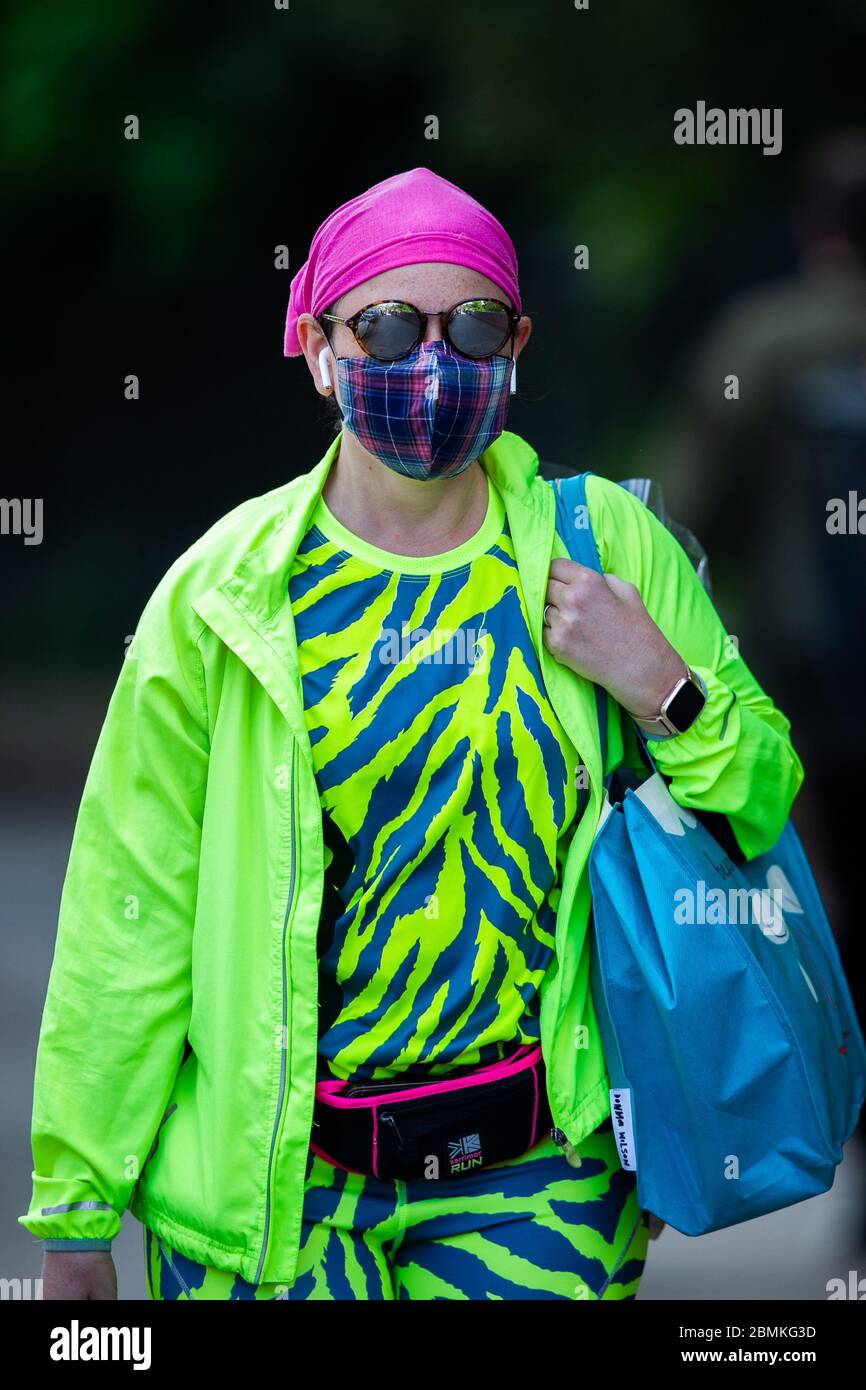 A woman wearing colourful clothing along with a face mask to protect against the Corona Virus, in Glasgow, Scotland, UK Stock Photo