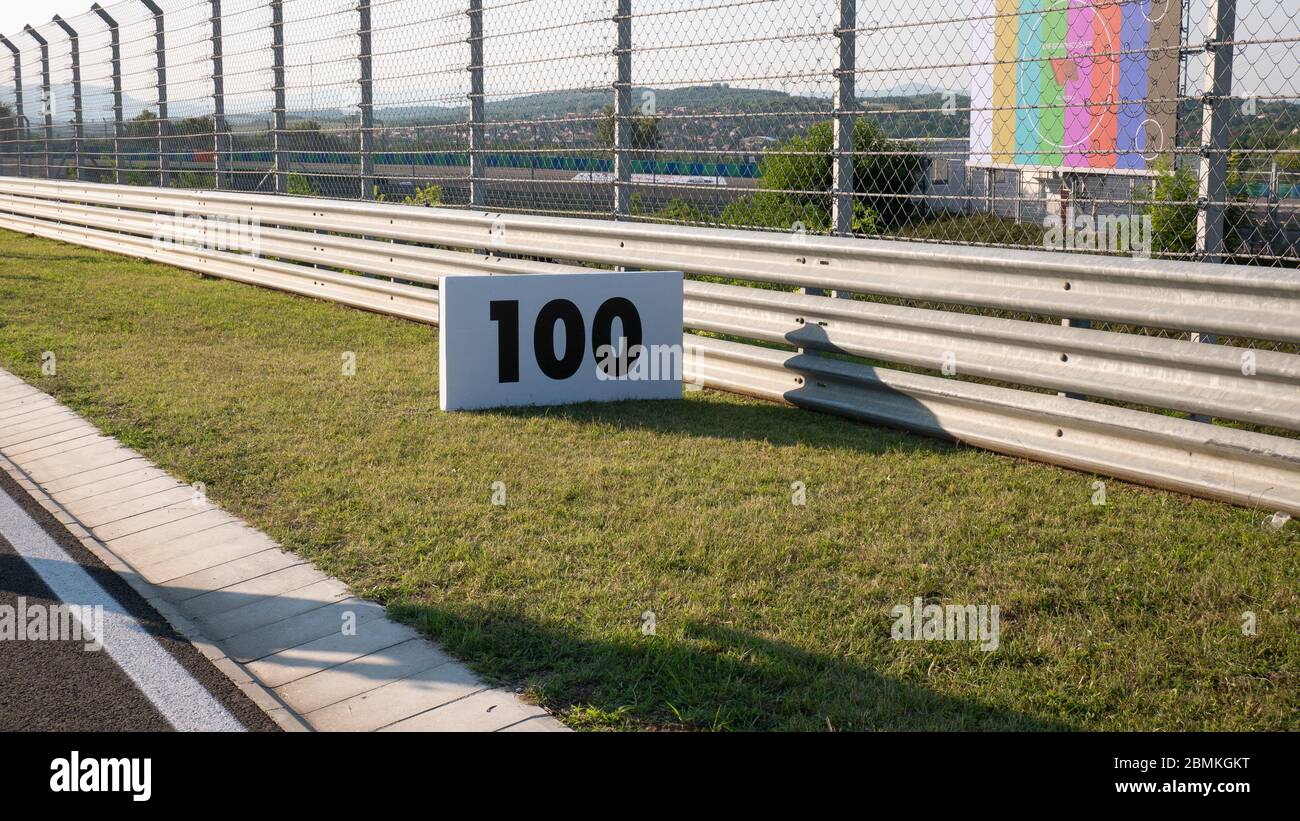 Warning sign or road sign for the maximum speed limit next to an empty road on a sunny summer day. Speed sign on a racetrack. Stock Photo