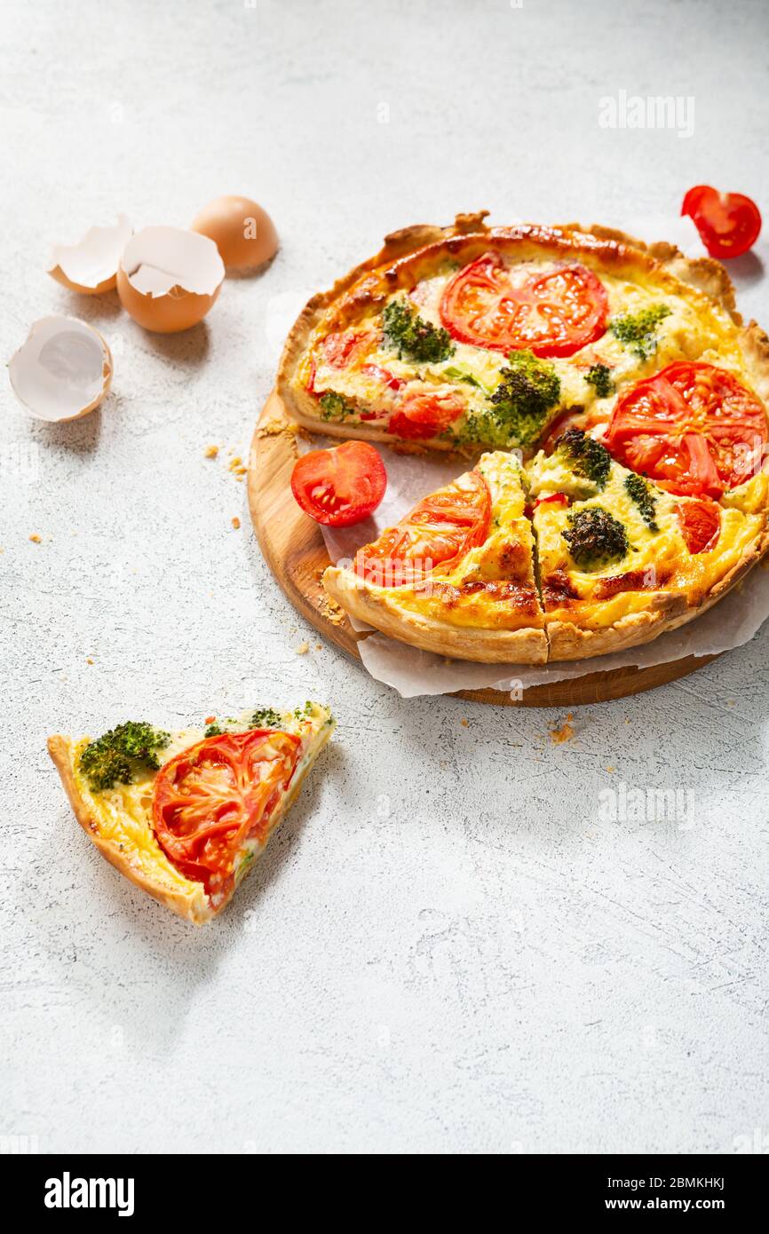 Sliced Quiche lorraine with broccoli and tomato on white surface Stock Photo