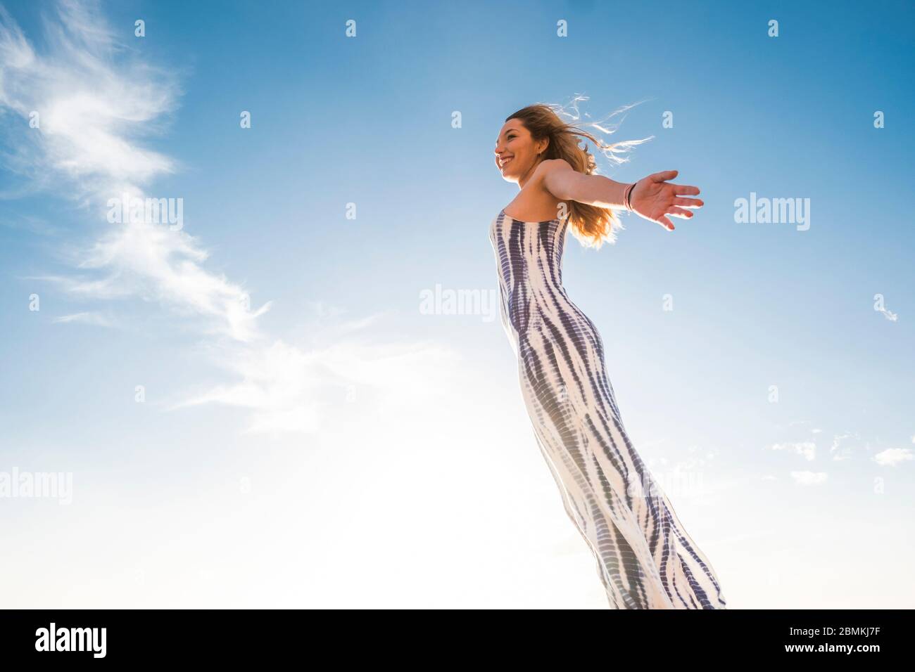 Young beautiful caucasian woman open arms and enjoy outdoor freedom with blue sky in background - joyful people and happy life lifestyle cheerful girl Stock Photo