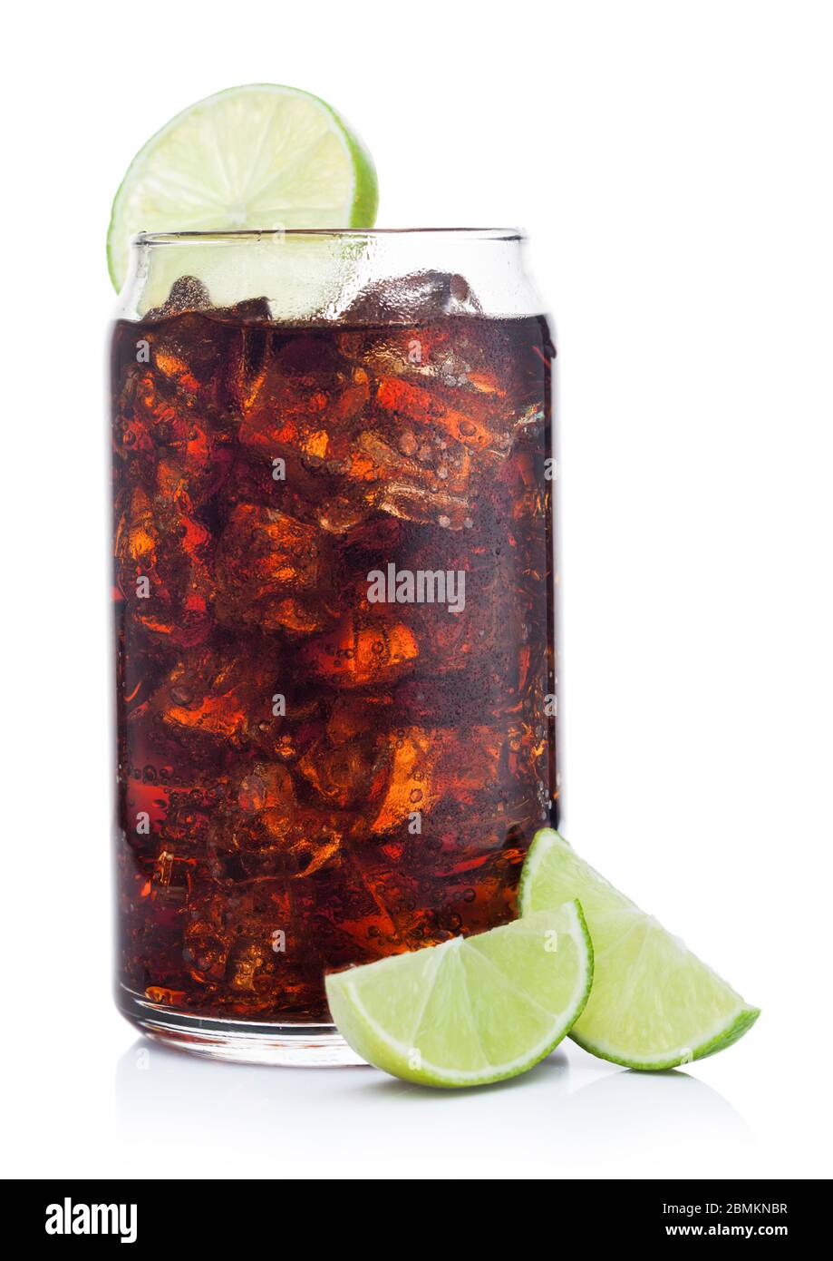 Cuba Libre Cocktail in tin shape glass with ice cubes and slices of lime on white background with raw limes Stock Photo
