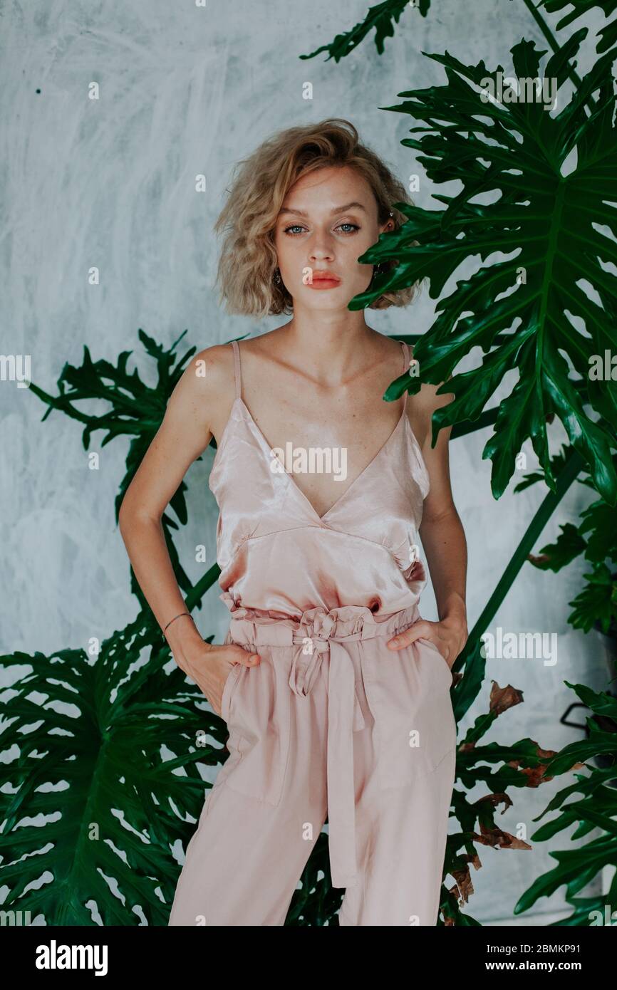 Portrait of a beautiful fashionable blonde woman in pink dress posing ...