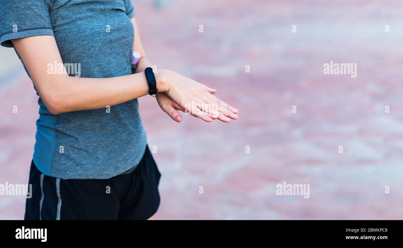 Woman using hand sanitizer as a covid 19 precaution and disinfection outdoors Stock Photo