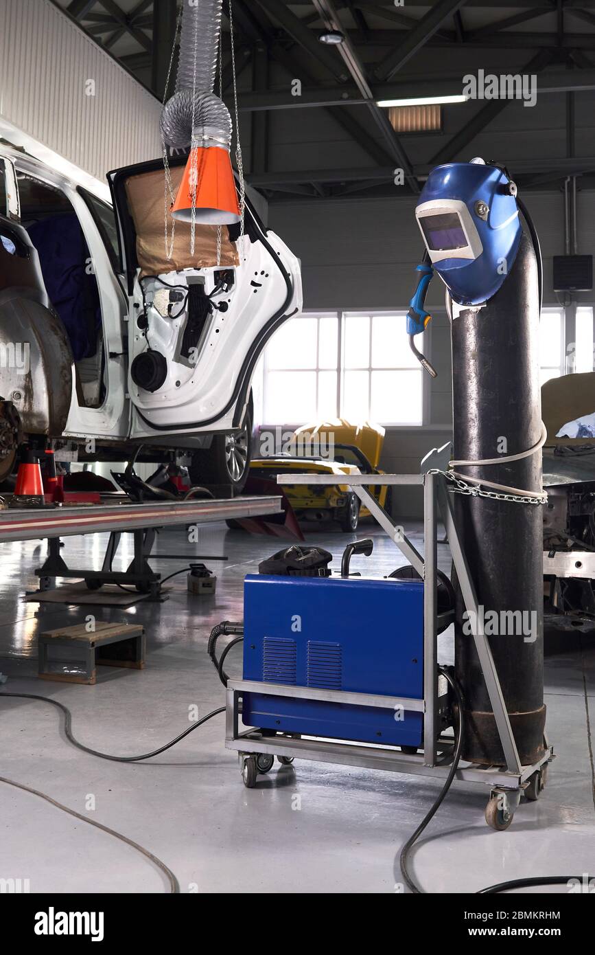 Welding equipment in a car repair station, helmet hanging on a gas tank, no people Stock Photo