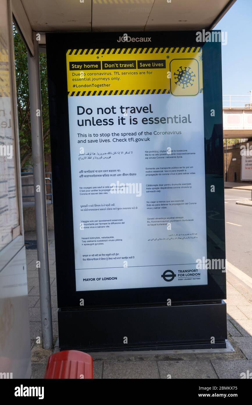 A four sheet illuminated poster on a bus stop telling people not to travel unless it is essential because of the Coronavirus outbreak. Stock Photo