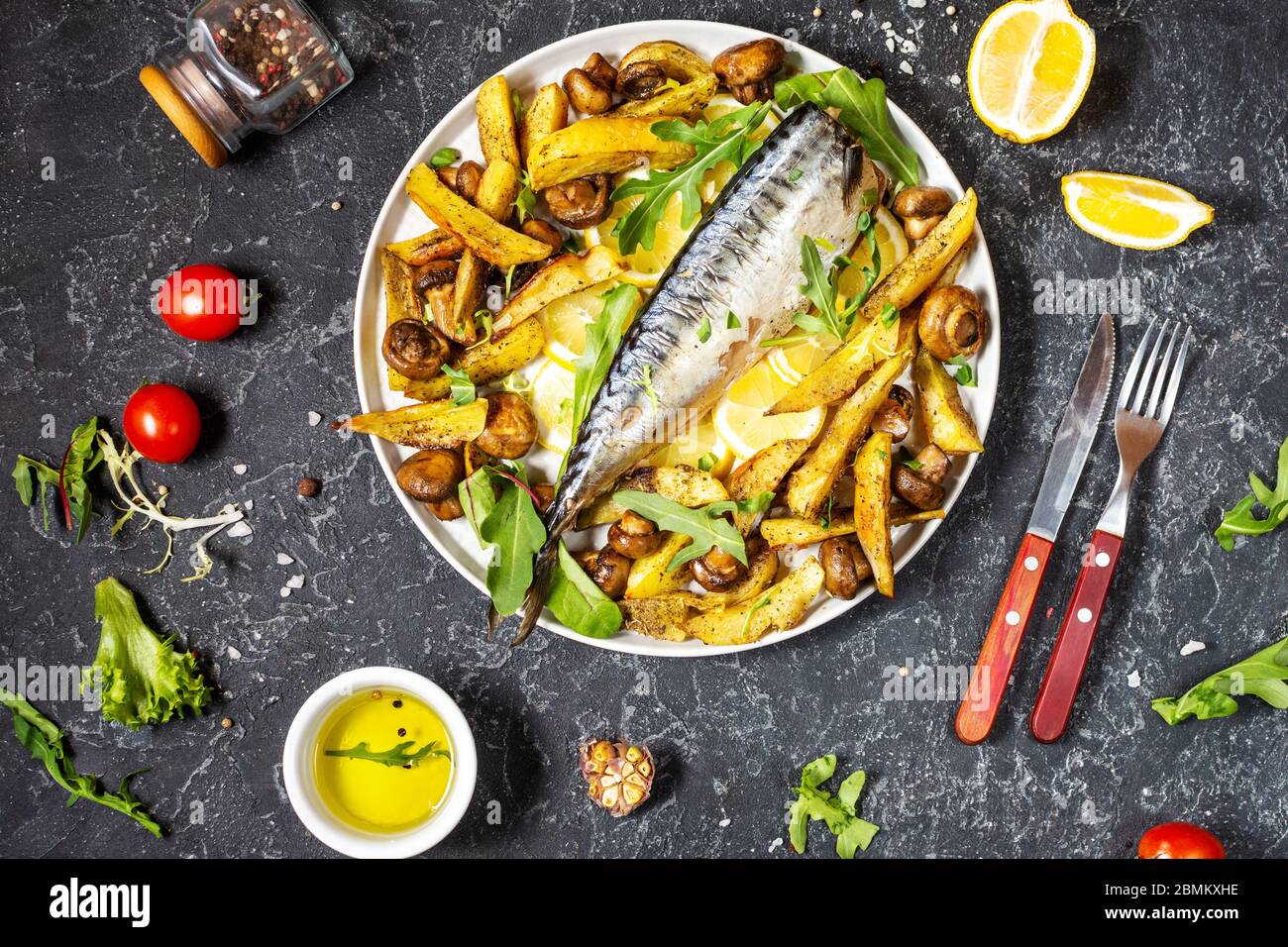 Baked mackerel with lemon, baked potatoes and mushrooms on a plate on