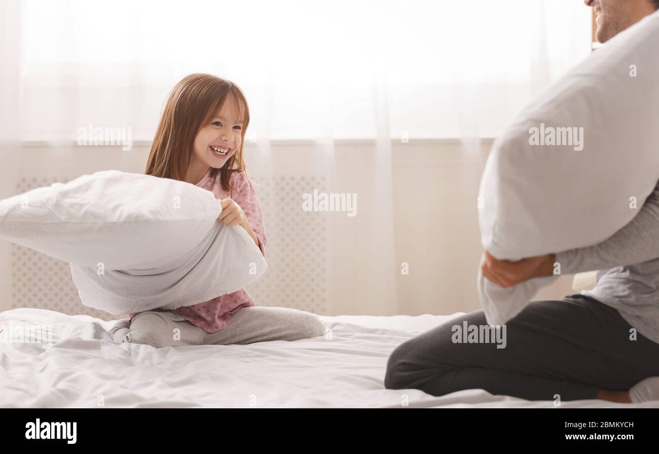 Close up of girl holding pillow, playing with dad Stock Photo
