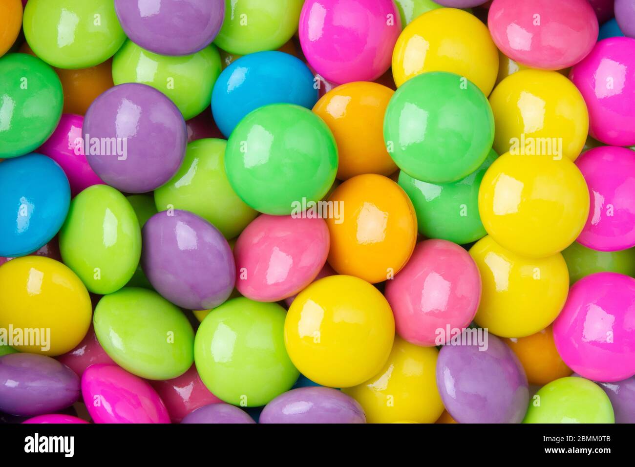 Pile of colorful sweet candy chocolates coated on white paper ...