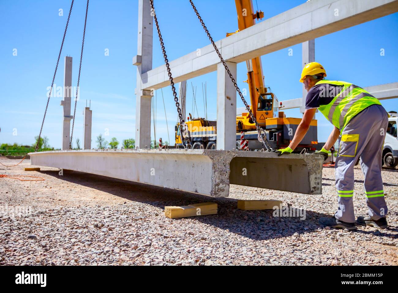 Workers are helping mobile crane to manage concrete joist for assembly ...