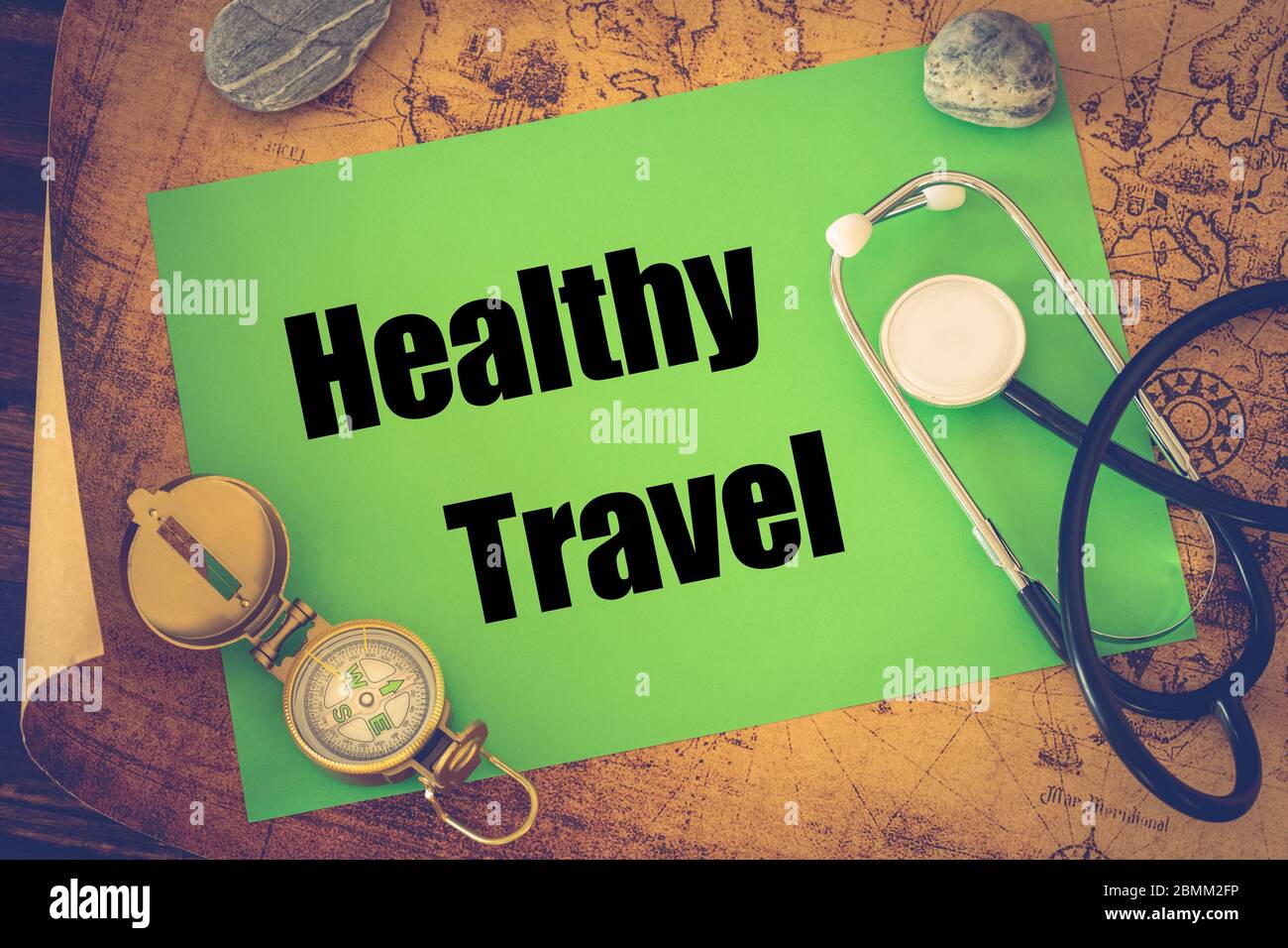 Medical stethoscope, compass and a card with the words 'Healthy Travel' on the background of an old map of the world, The concept of safe travel Stock Photo
