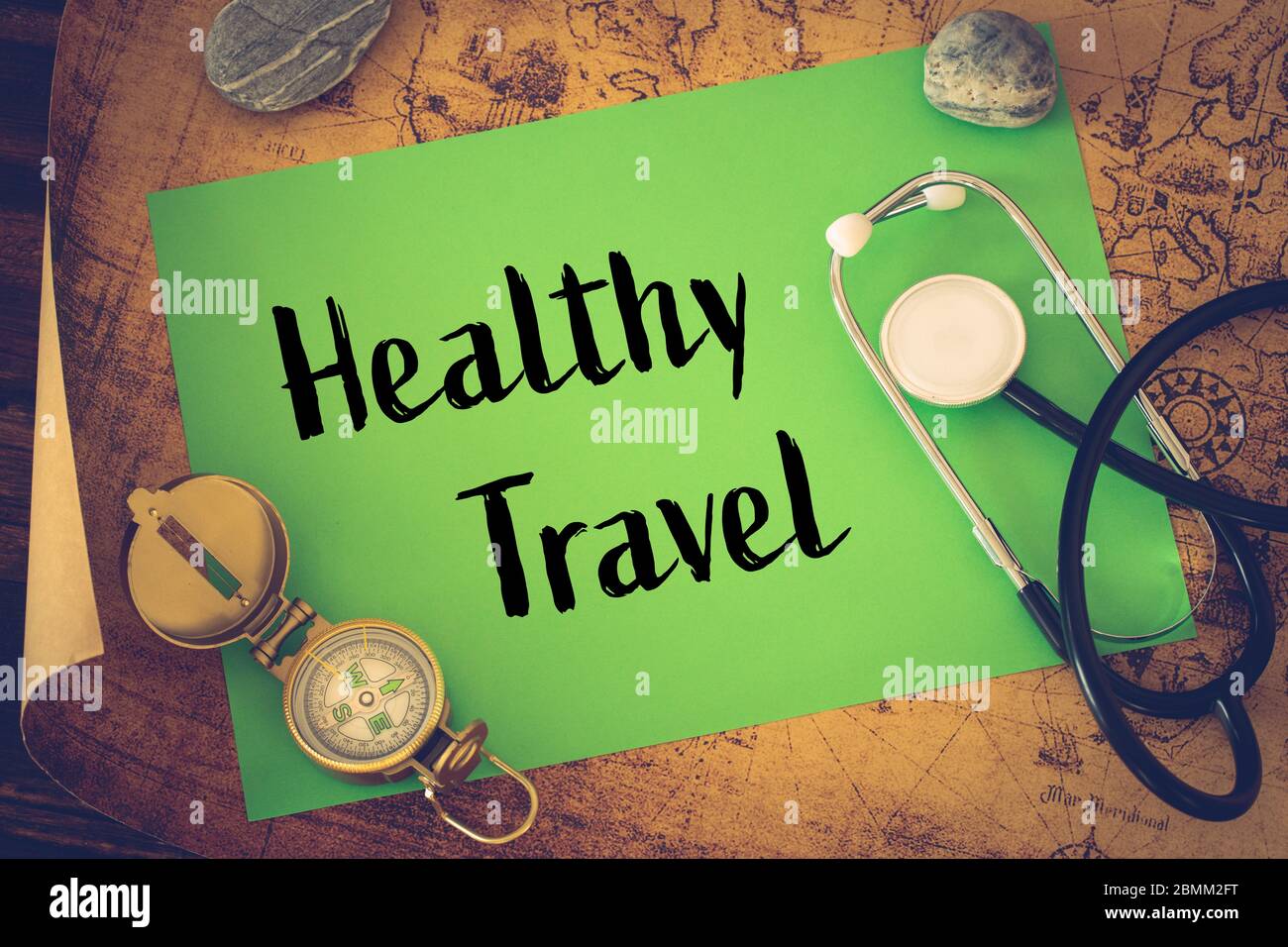 Medical stethoscope, compass and a card with the words 'Healthy Travel' on the background of an old map of the world, The concept of safe travel Stock Photo