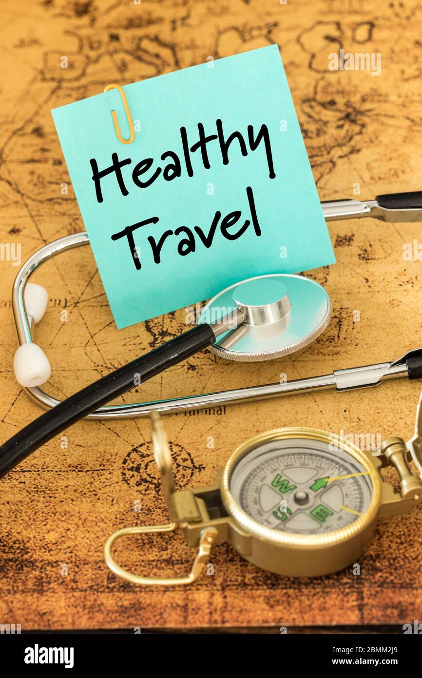 Medical stethoscope, compass and a card with the words 'Healthy Travel' on the background of an old map of the world, The concept of a safe vacation Stock Photo