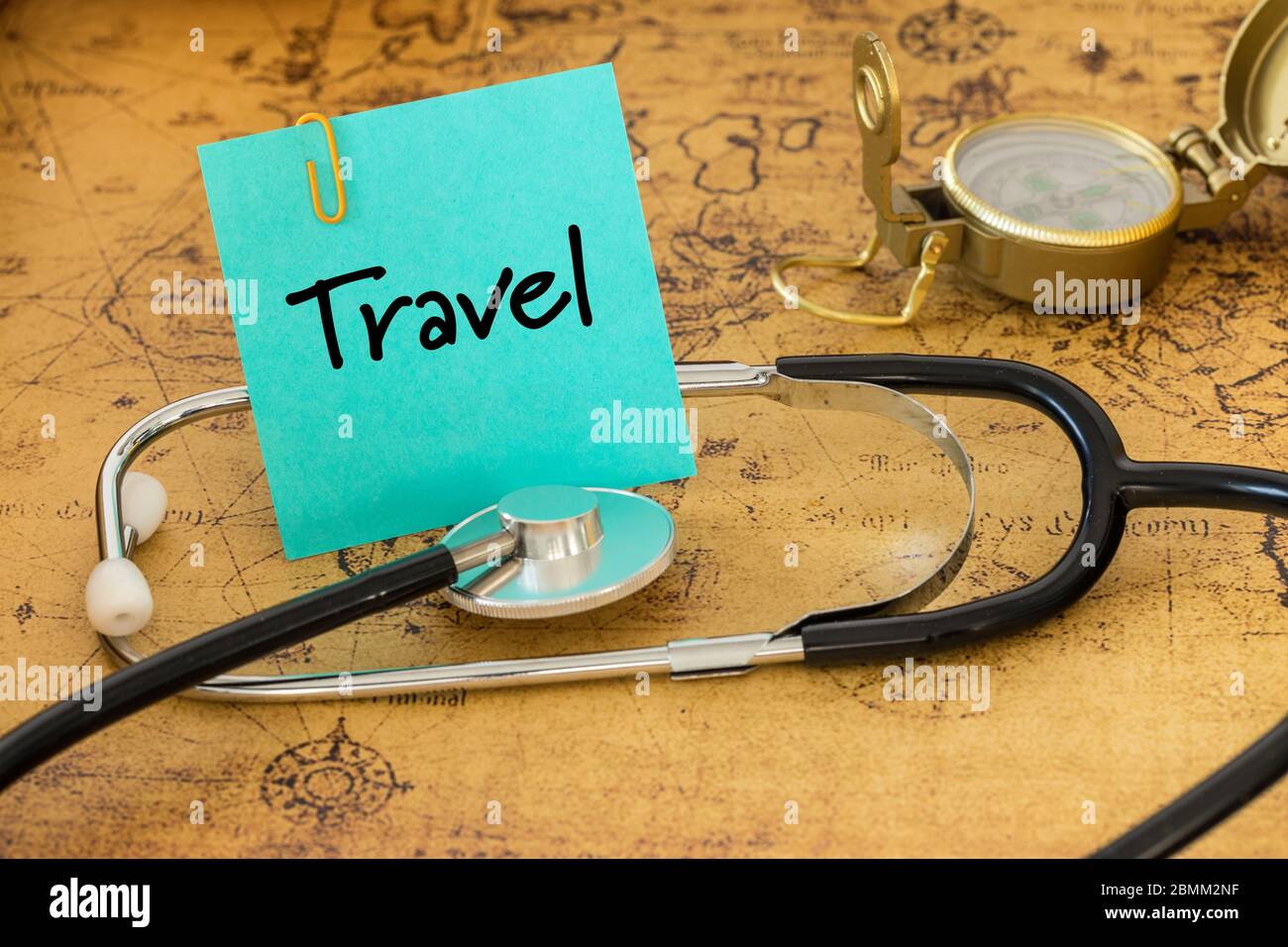 Medical stethoscope, compass and a card with the words 'Travel' on the background of an old map of the world, The concept of safe journey Stock Photo