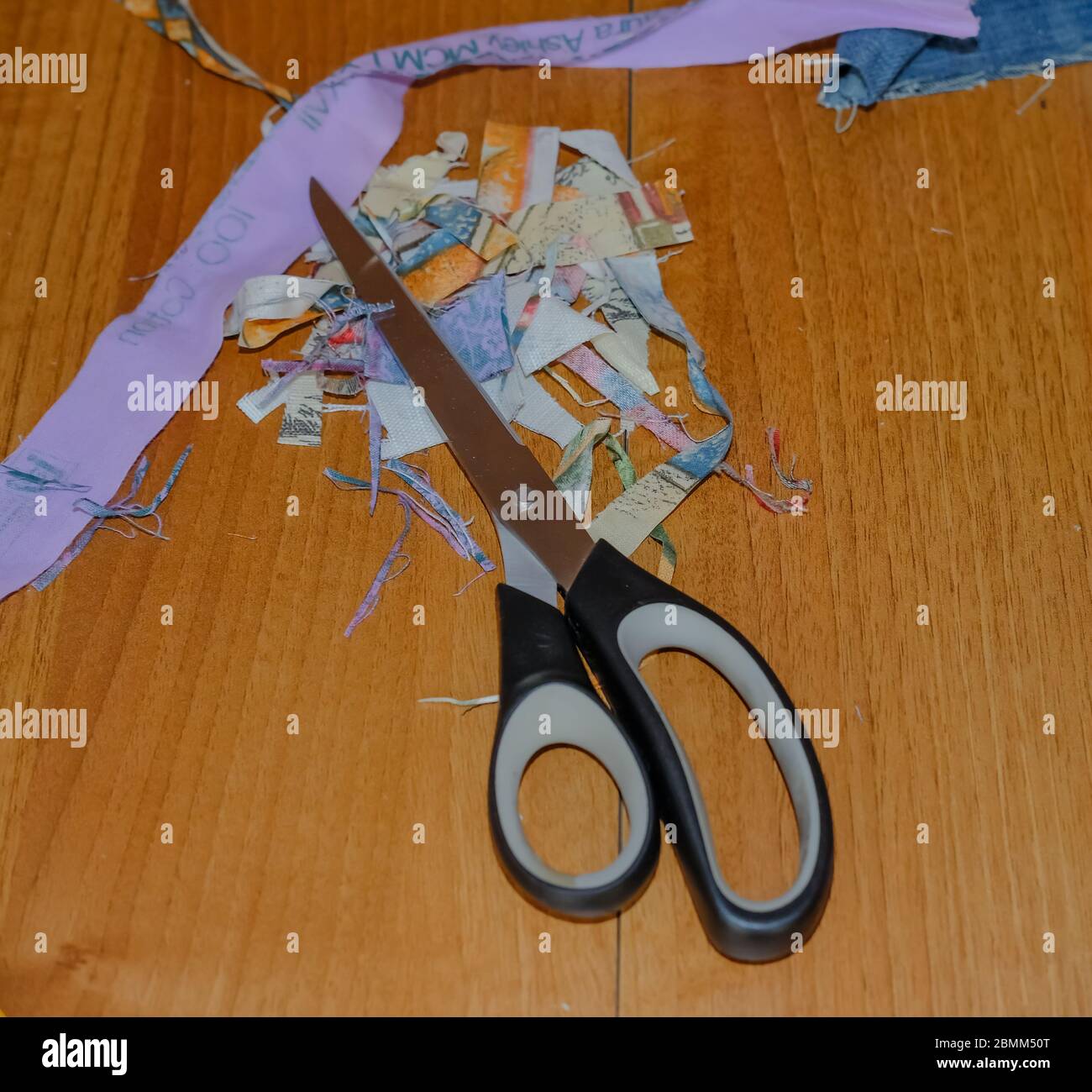 31 Crafting at home. Top down view of crafting scissors and fabric on a wooden table during a home sewing project Stock Photo