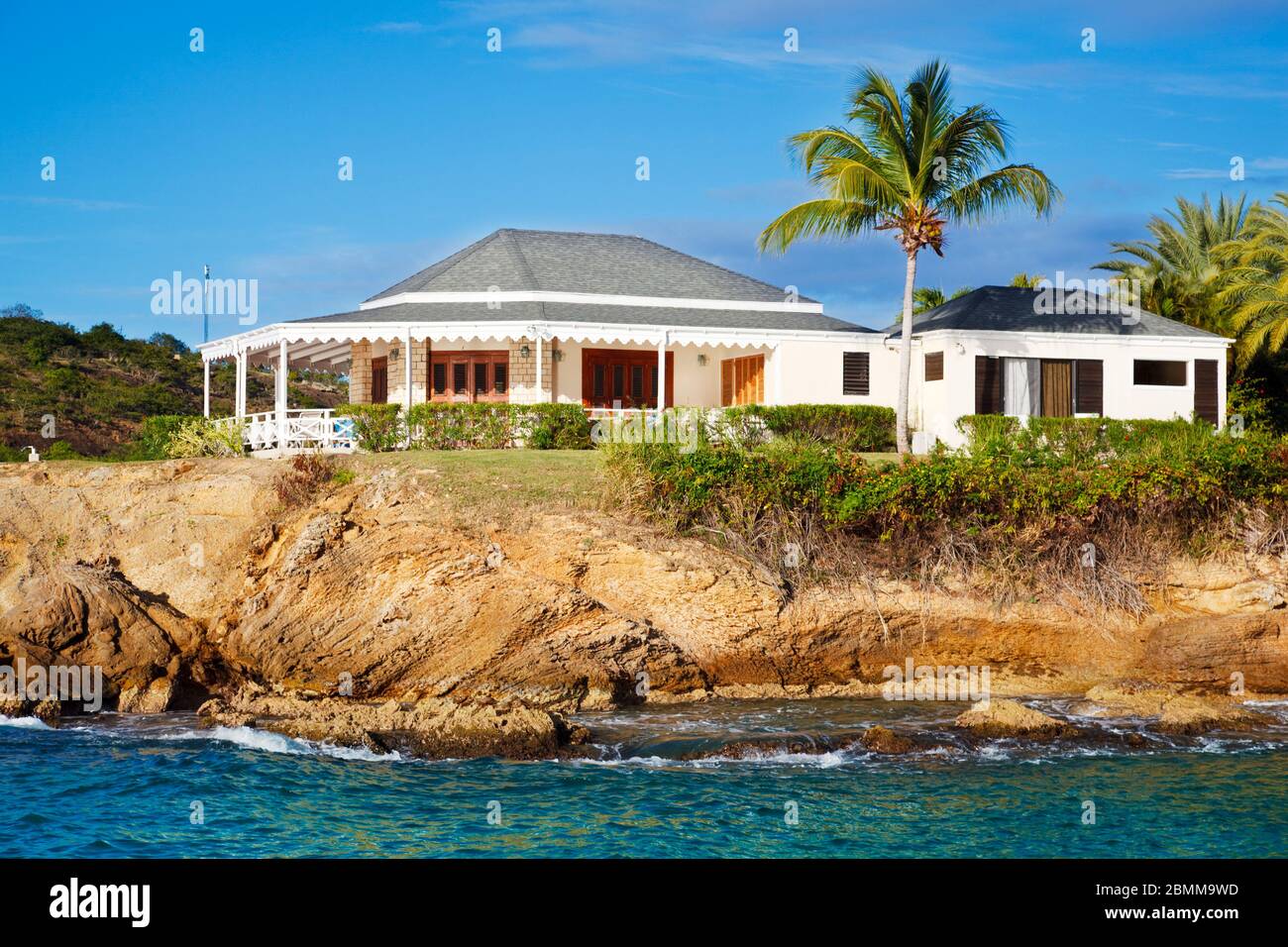 A little caribbean villa on a small cliff with a coconut palm tree. Stock Photo