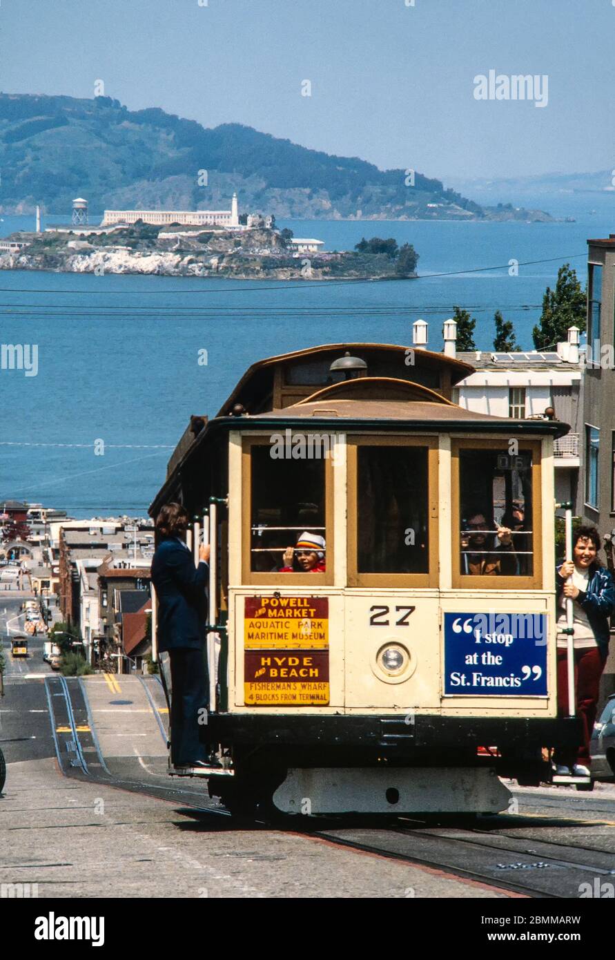 San Francisco, USA - May 1980: Cable car climbing steep street with Alcatraz island visible in the background.  Scanned 35mm film. Stock Photo