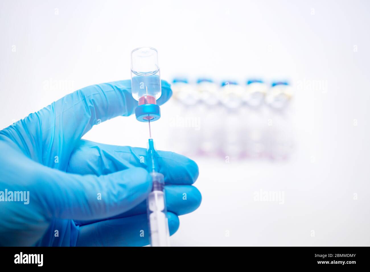 Scientist hand in blue gloves holding coronavirus, covid-19 vaccine disease, preparing for human clinical trials vaccination shot. Medicine and drug c Stock Photo