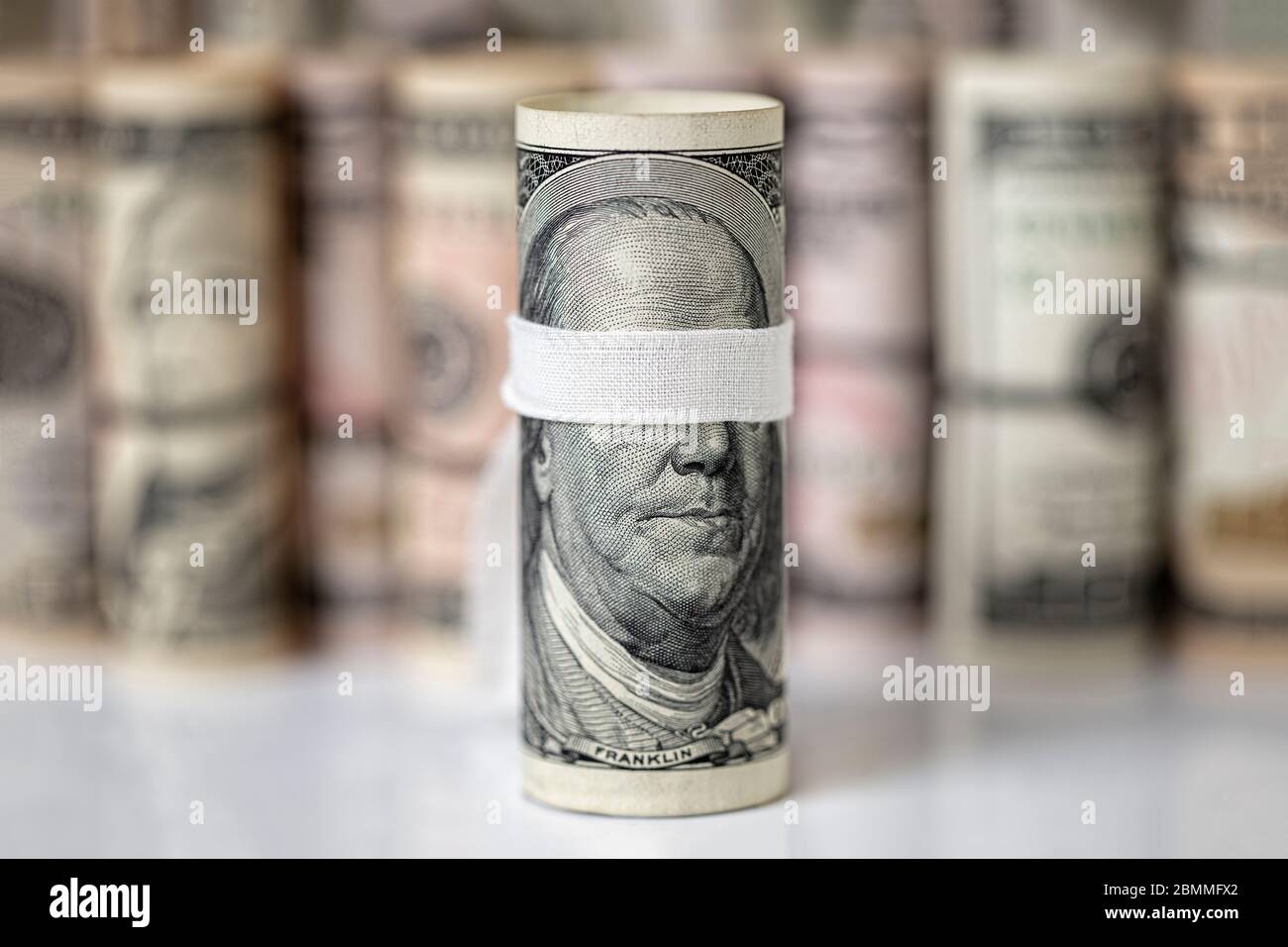 Blindfolded One hundred US dollar rolled bill banknote, with of focus ...