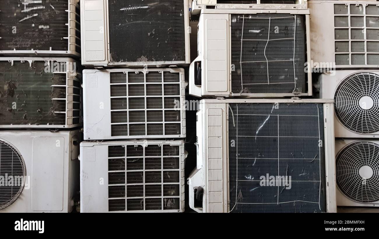 A group of dirty, dusty and broken air conditioning compressors are
