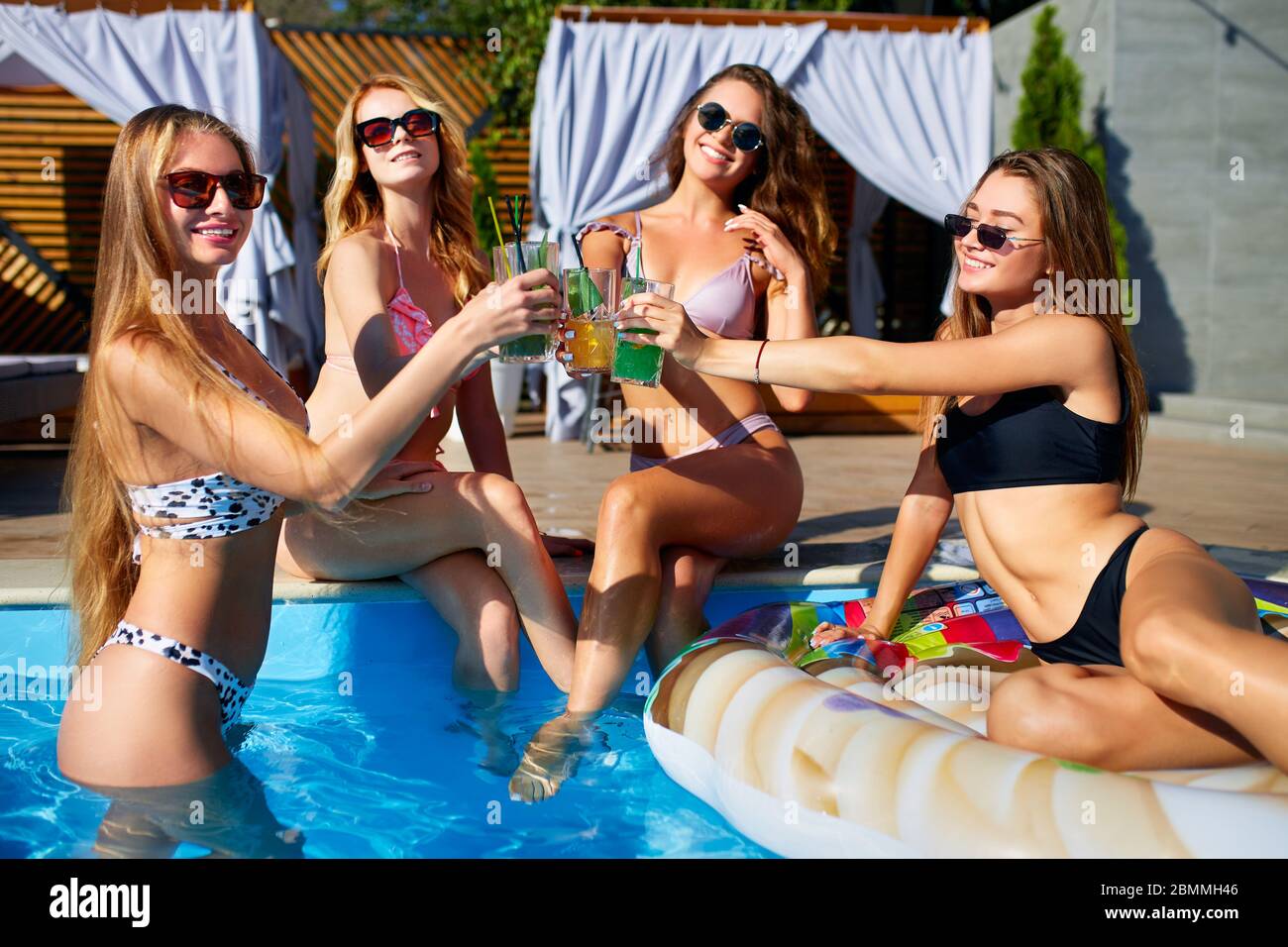 Happy attractive women in bikini have fun on poolside summer drinking fresh colorful cocktails sitting by the swimming pool. Female friends in Stock Photo - Alamy