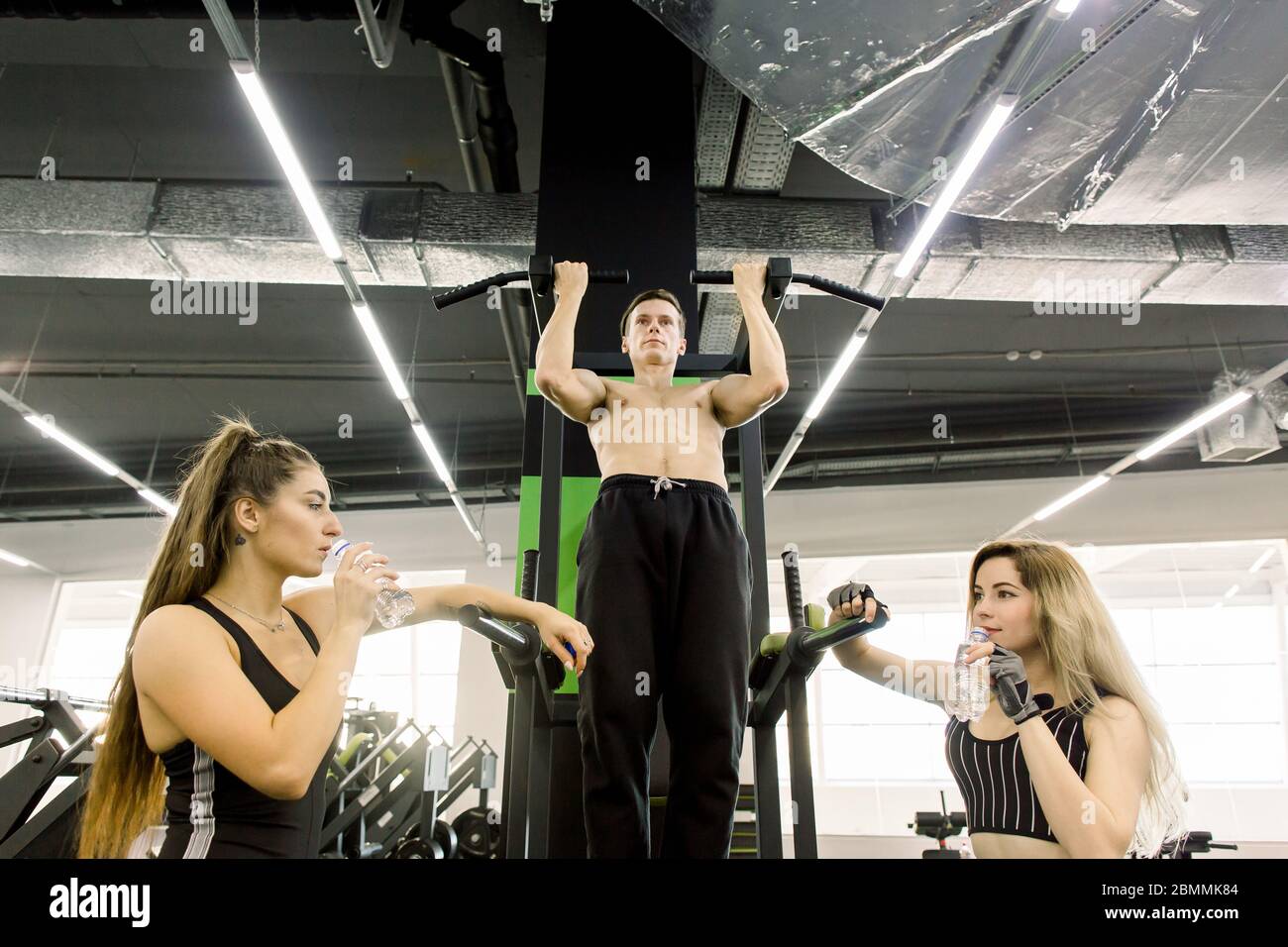 shot of a muscular Caucasian male athlete doing pull ups at the gym ...