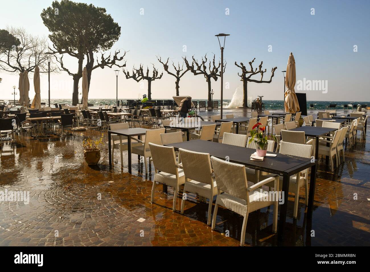 View of the lake shore with empty outdoor café in a windy day with high waves flooding the lakeside, Garda, Verona, Veneto, Italy Stock Photo