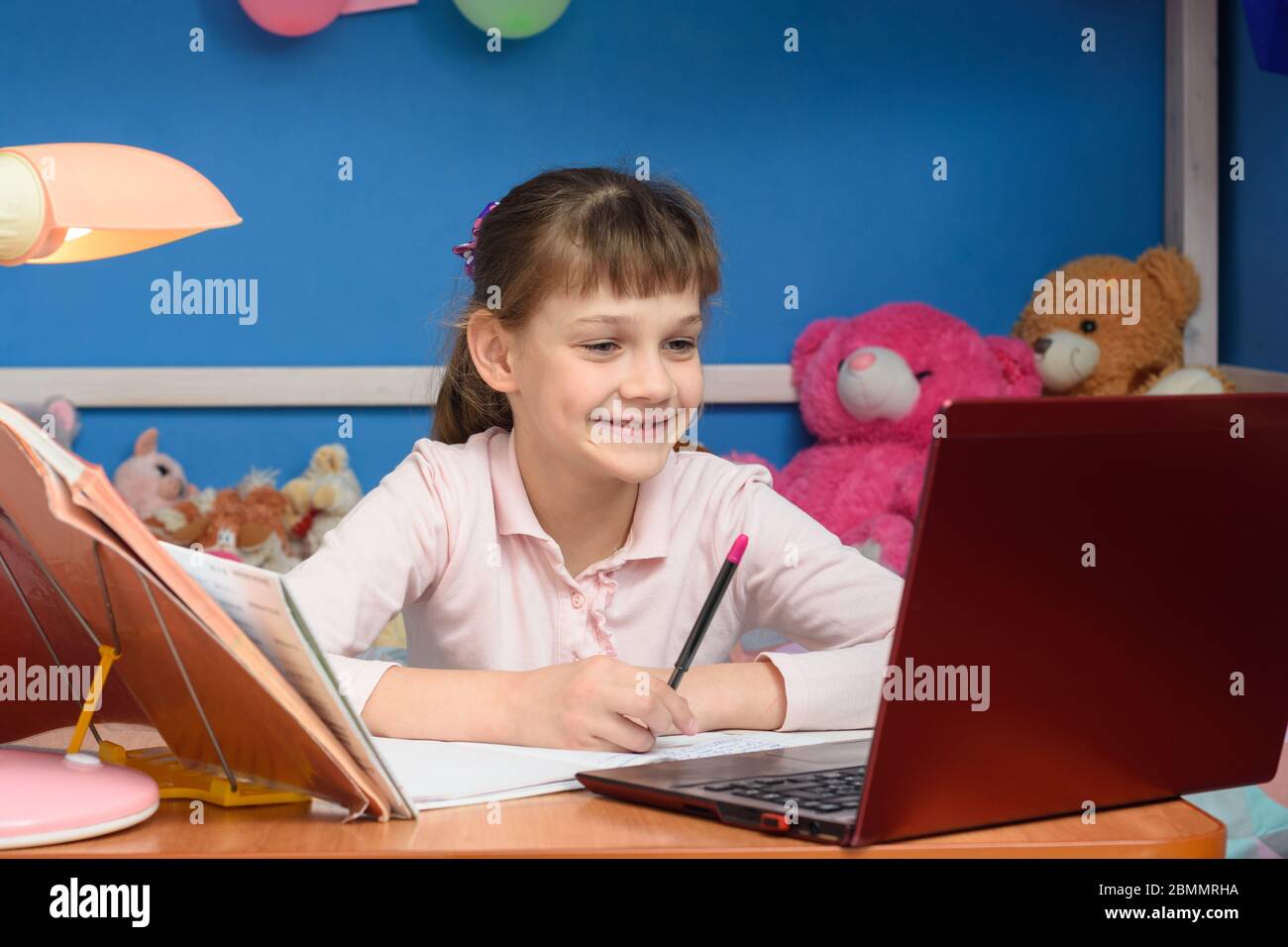 Smiling girl at table at home studying at school Stock Photo - Alamy