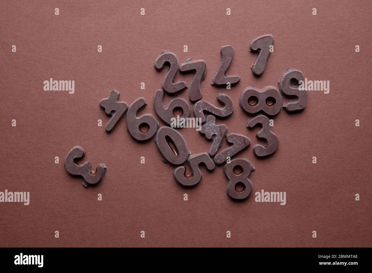 an artsy studio shot of chocolate numbers against a brown background Stock Photo
