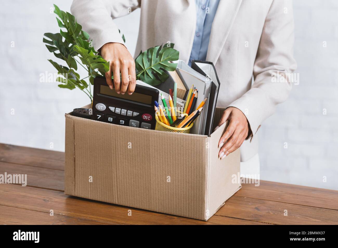 Leaving work concept. Closeup of African American woman with cardboard box of stuff at office Stock Photo