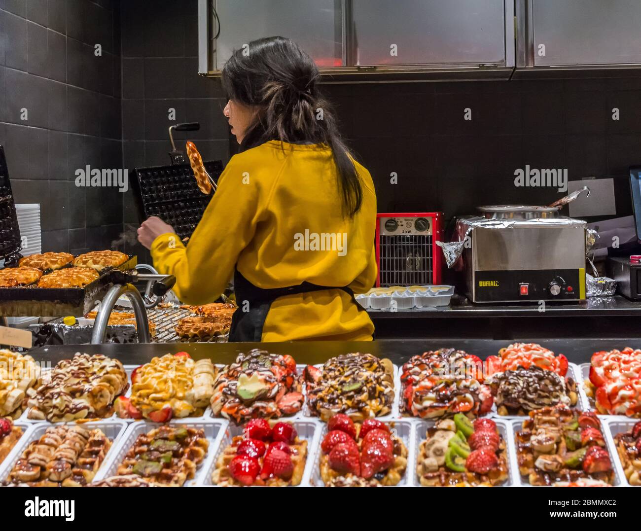 woman prepared Belgium waffle on Christmas fair in Brussels, Belgium on December 30, 2019. Stock Photo