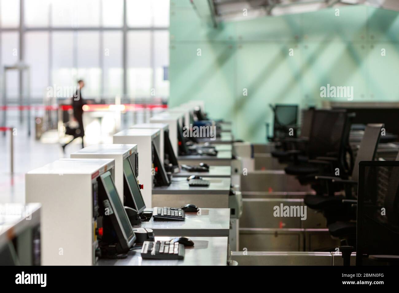 Row of check-in desks with computer monitors at empty airport terminal due to coronavirus pandemic/Covid-19 outbreak. Selective focus. Travel ban. Stock Photo