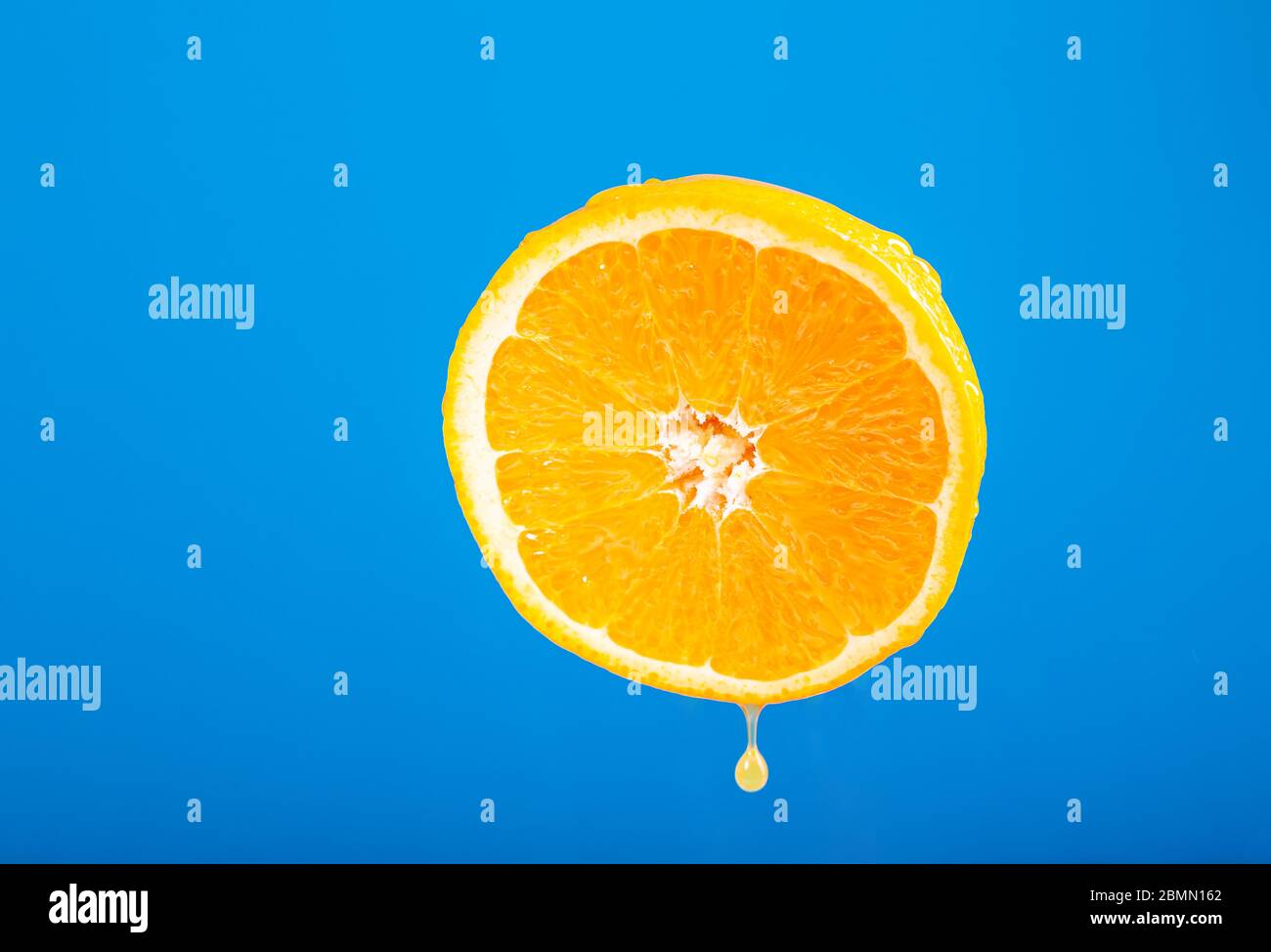 Fresh orange. Fruits on a blue background. Cut orange. Fruit juice drops. Vegetarian dish. Fresh citruses. Drops of water on the skin. Dripping fruit Stock Photo