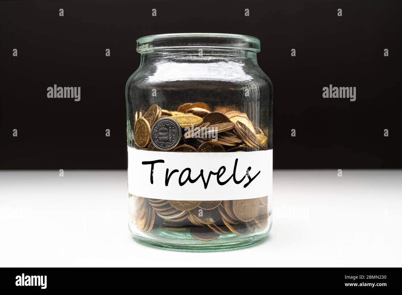 Coins in a jar with travels text on a white label. Savings abstract concept. Copy space. Stock Photo