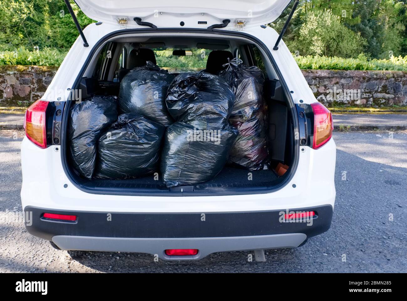 Black plastic bin bags full tied and in car boot with door open for fly