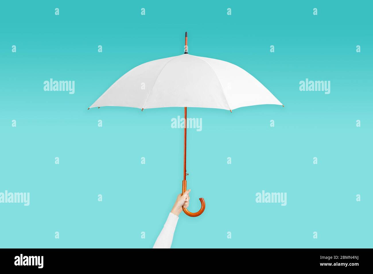 Hand holding open white umbrella on blue background Stock Photo
