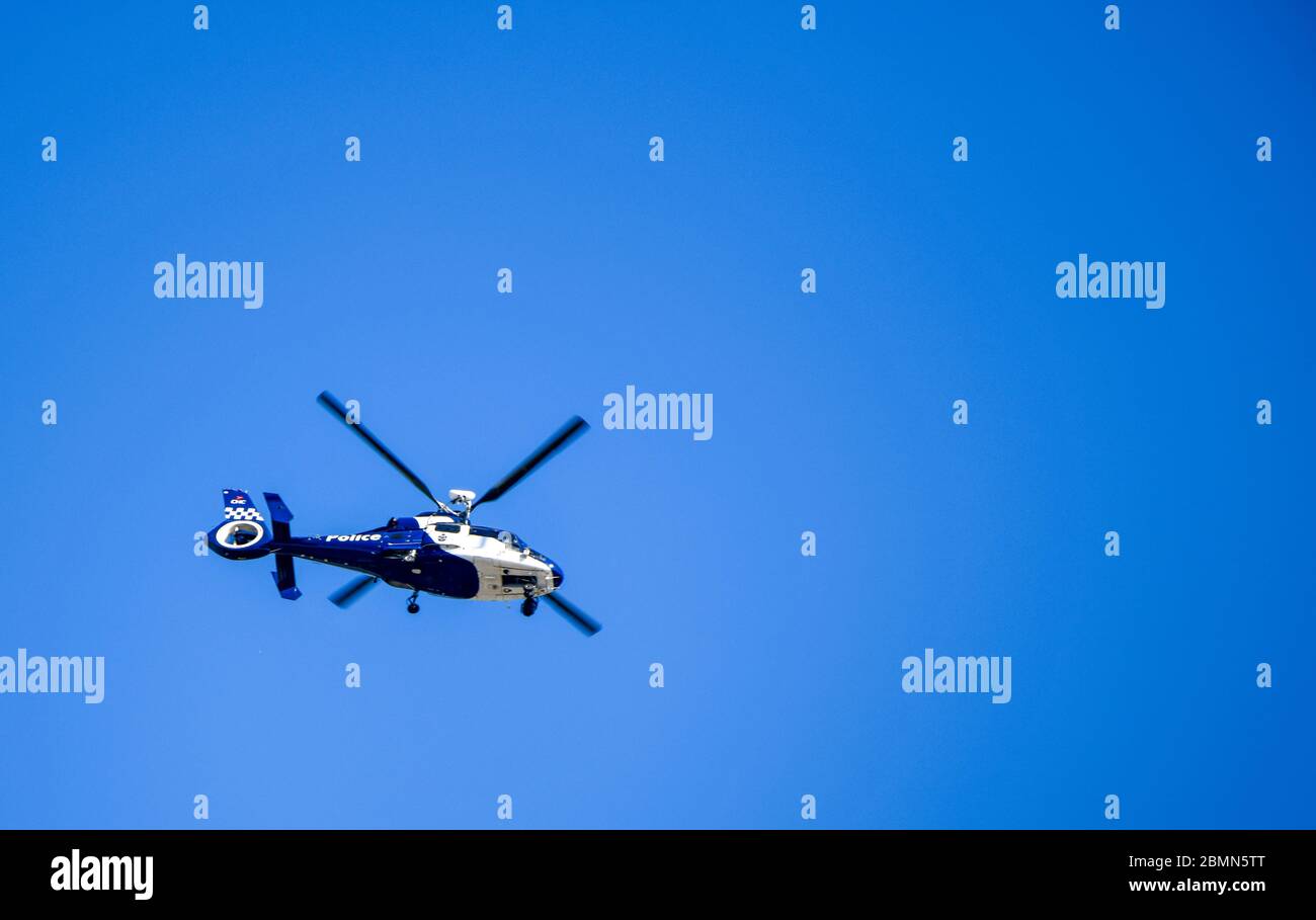 Police Helicopter Aircraft Hovering in Blue Sky Tracking Emergency Stock Photo