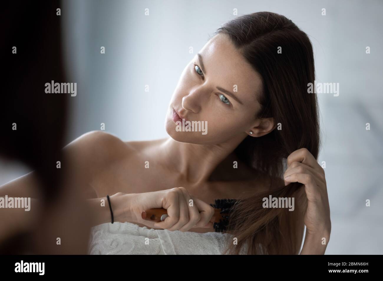 Woman combing hair looking dissatisfied by naughty tangled hair Stock Photo