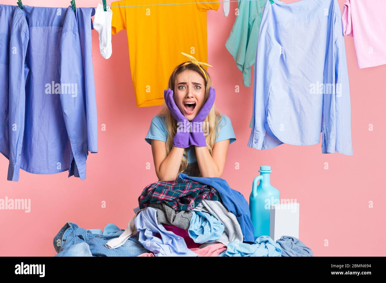 Cry of despair from housewife. Girl with heap of dirty clothes Stock
