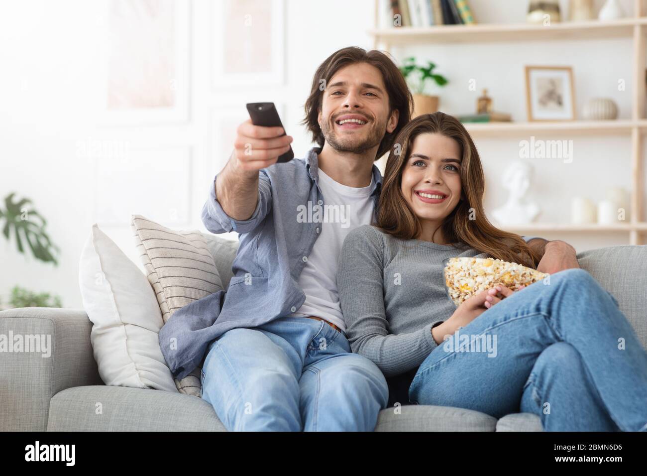 Lovely couple watching TV at home and eating popcorn Stock Photo - Alamy