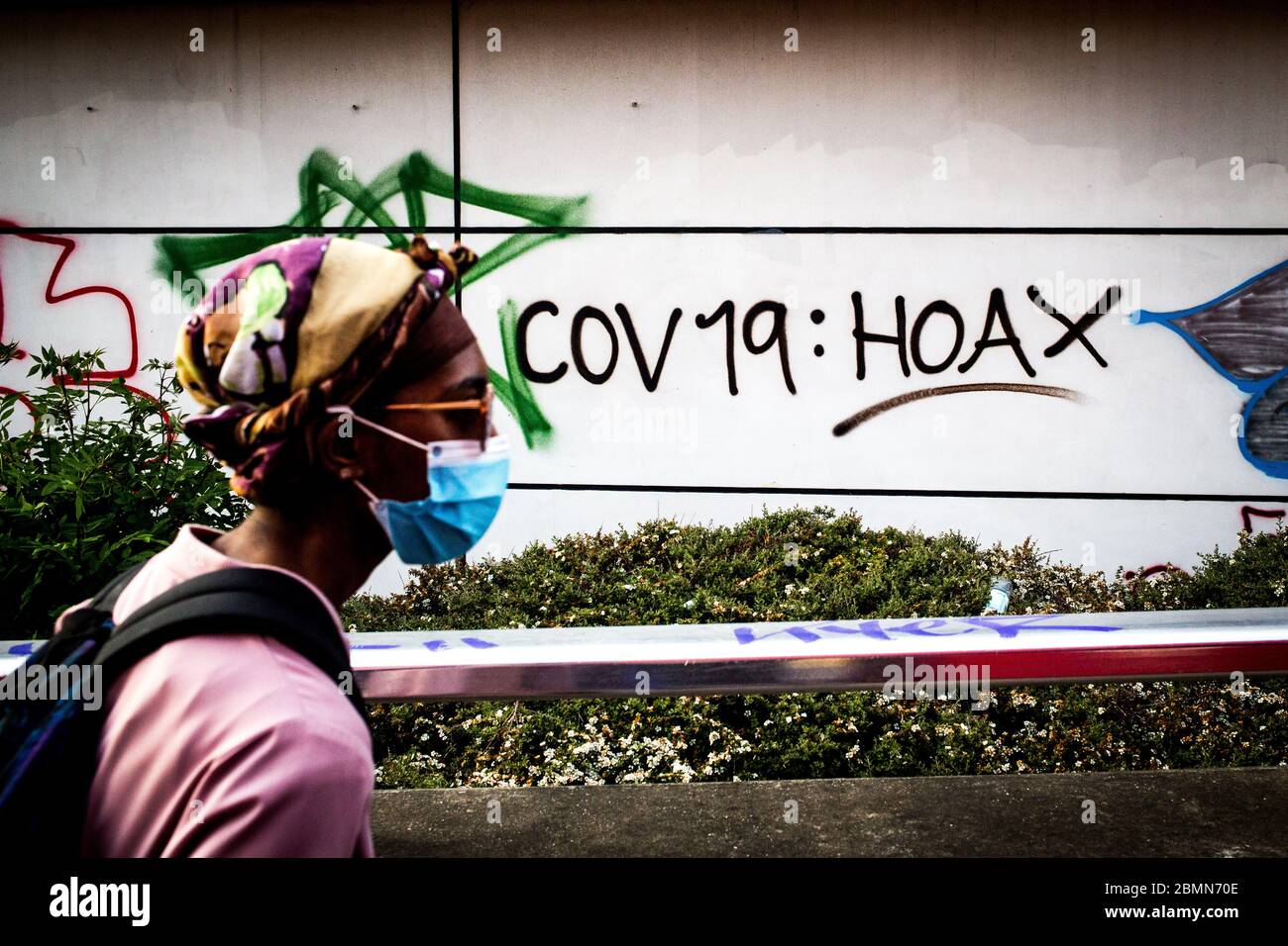 London UK 9th May 2020 A woman wearing a surgical mask walks past anti- covid-19 graffiti in south London. Stock Photo