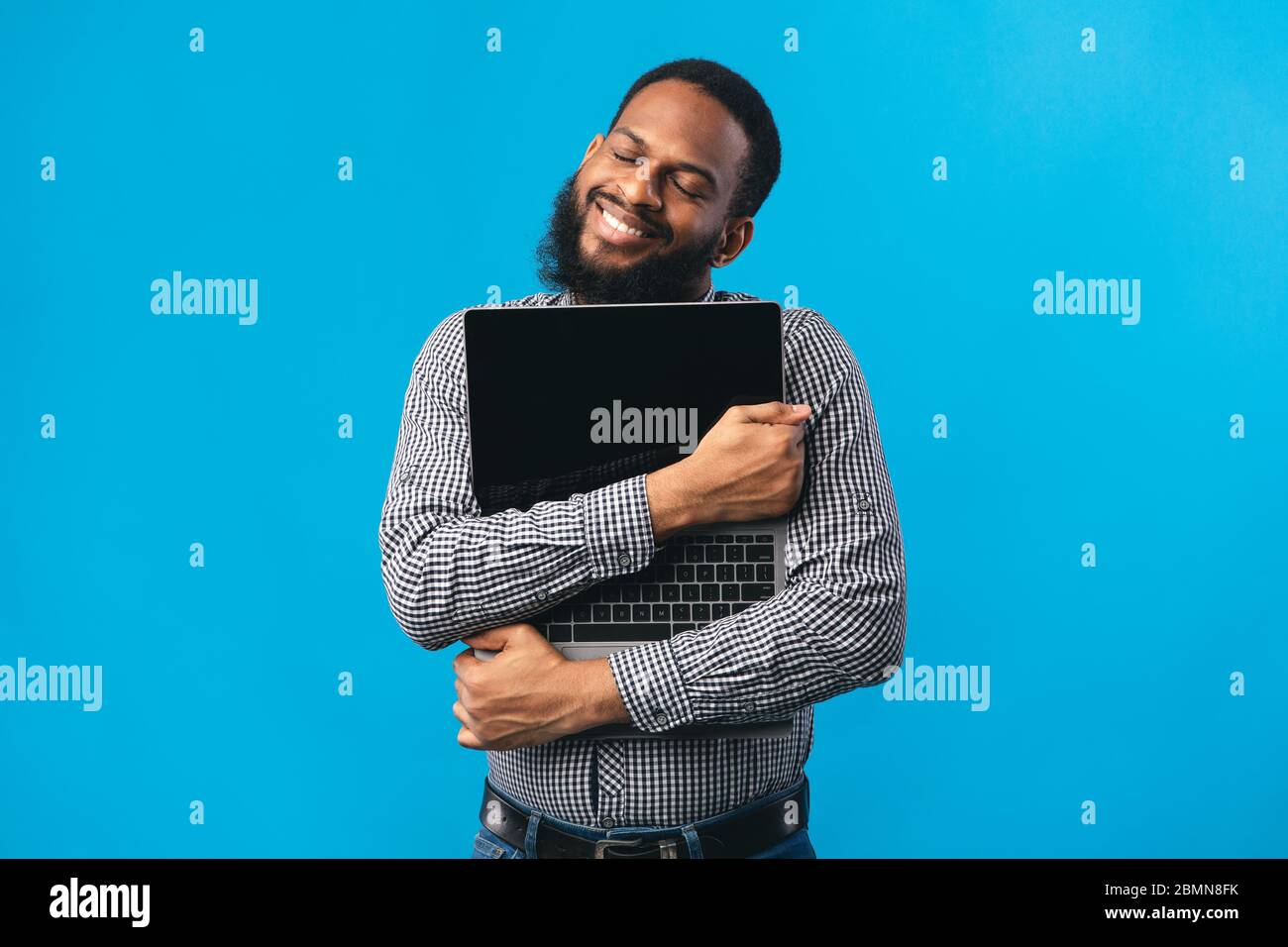 Smiling african american guy holding personal computer Stock Photo
