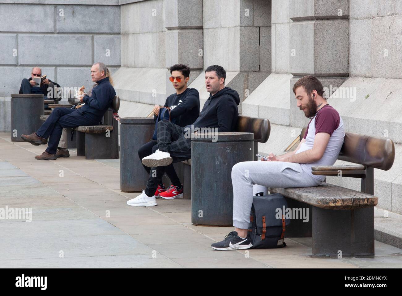 London, UK: although strictly speaking sitting on public benches is not  allowed under social-distancing advice, these groups have at least kept  their distance from each other. Prime Minister Boris Johnson is poised