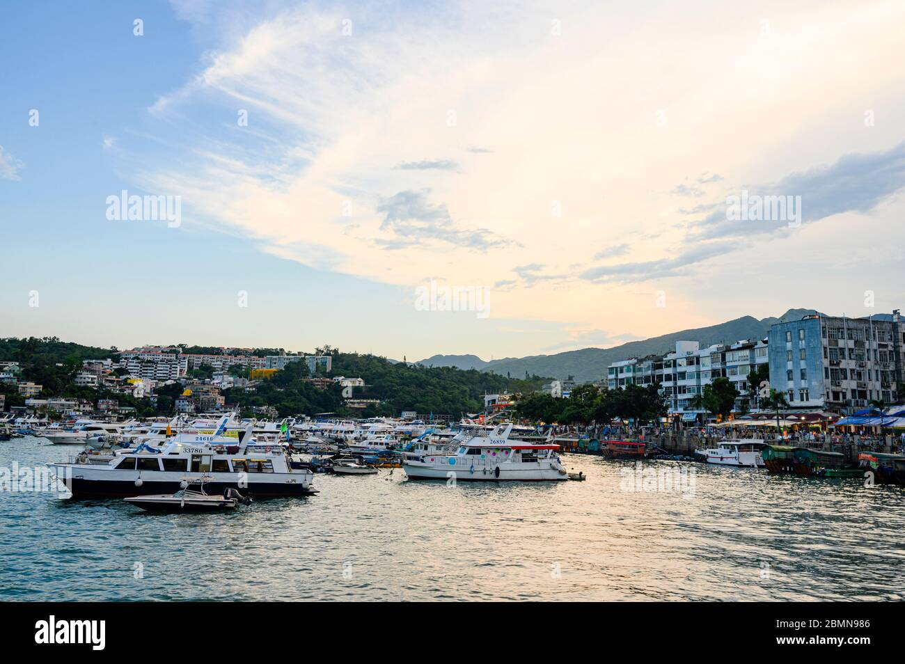 The sunset view of the pier at Sai Kung, Hong Kong with many yachts and boats parking around. Stock Photo
