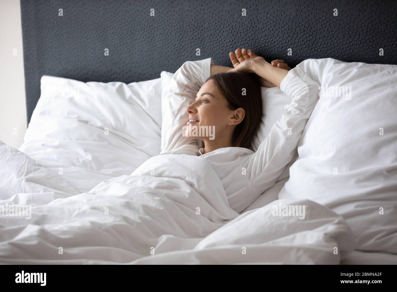 Woman wake up lying in bed dreaming enjoy new day Stock Photo