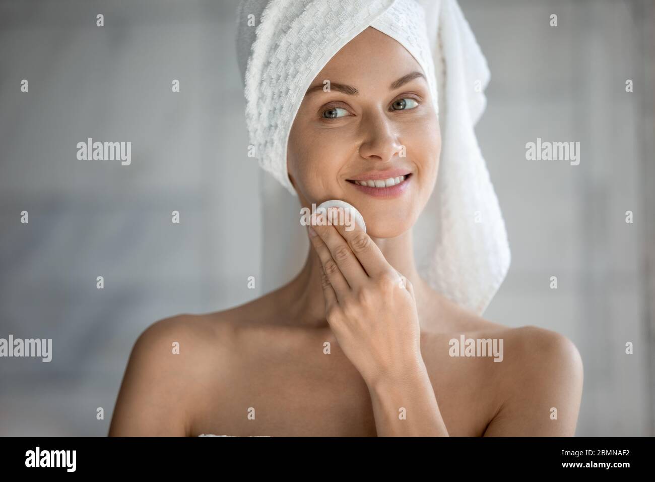 Woman holding cotton pad uses gel biphasic cleanser removing makeup Stock Photo