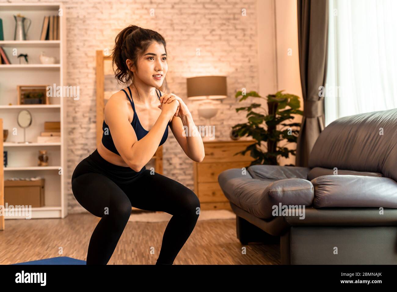 Young fit Asian woman working out at home. Beautiful female athlete training for legs muscles with squats exercise move Stock Photo Alamy