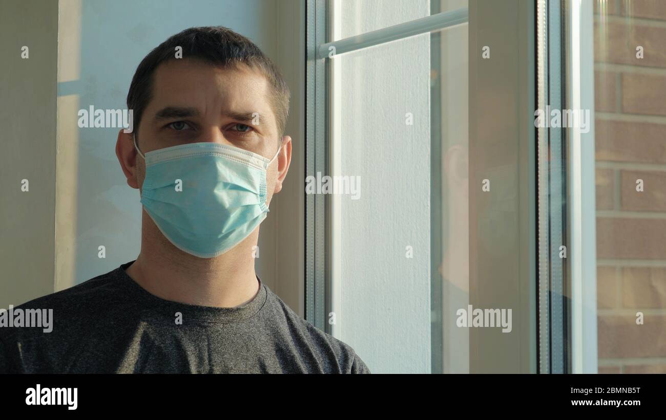 Man in a medical mask while at home isolation Stock Photo