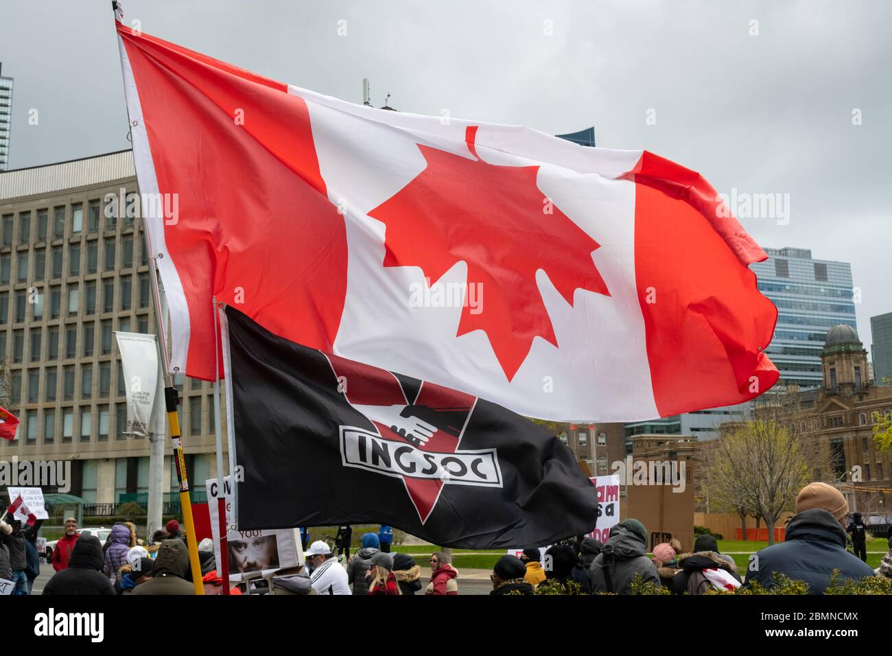 An INGSOC flag from George Orwell's 1984 flies alongside an upside-down Canada Flag outside Queen's Park at a protest against the COVID-19 Shutdown. Stock Photo